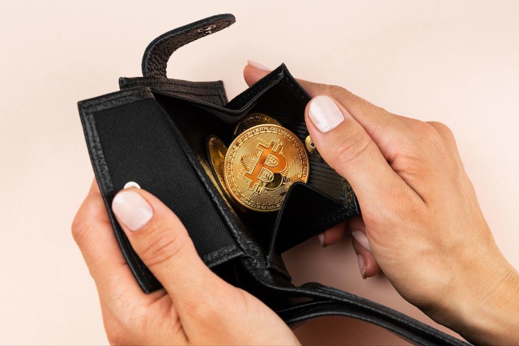 Hands holding an open wallet with a single Bitcoin coin inside.
