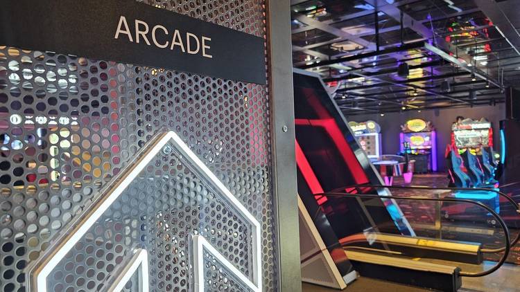 A neon arrow pointing the the ARcade, with traditional games illuminated in the background.